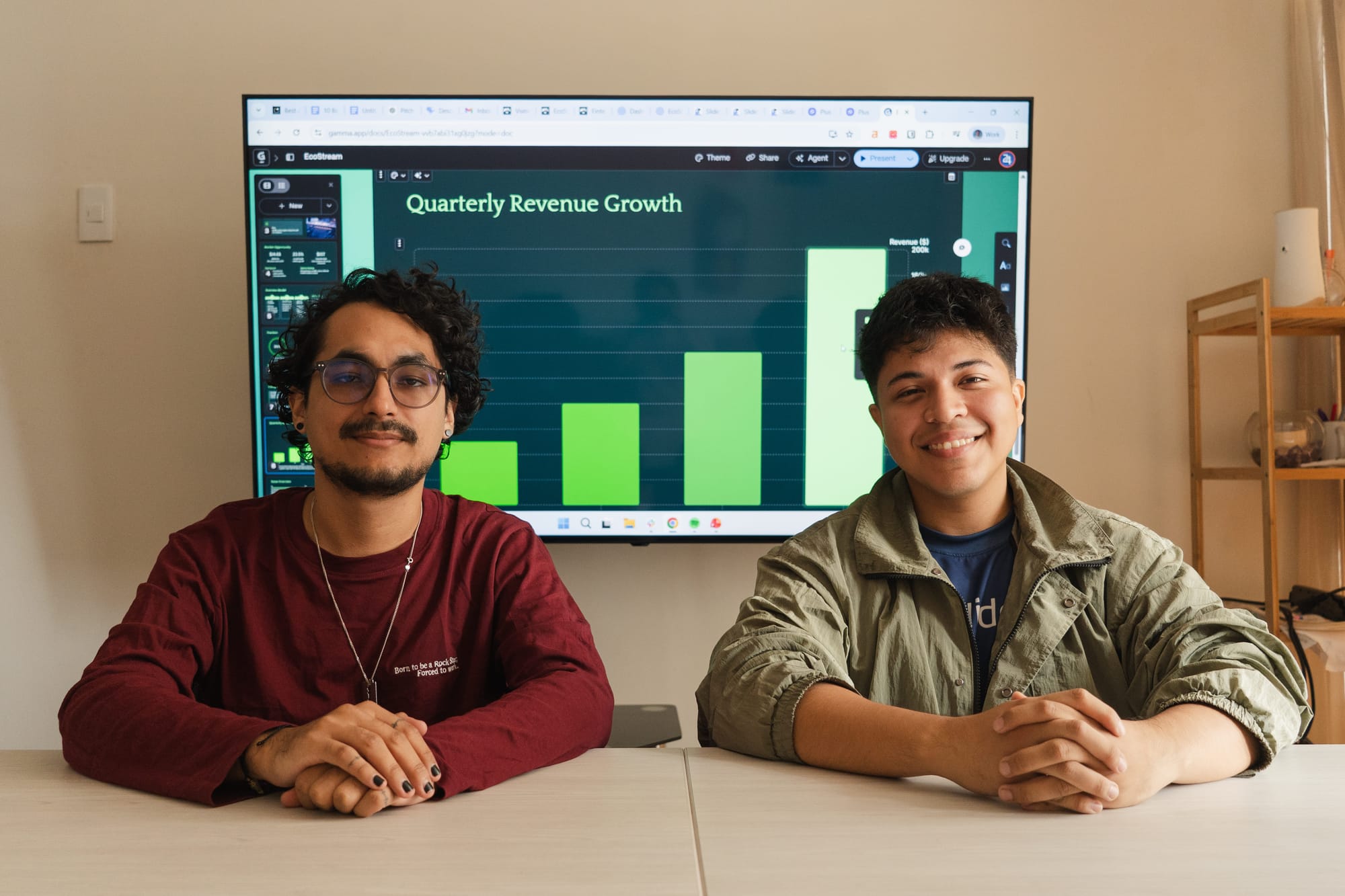24Slides Marketing Designers Gabriel Morales and Leonardo Acaro sitting in front of a monitor displaying a Gamma AI generated presentation chart during a benchmark test.