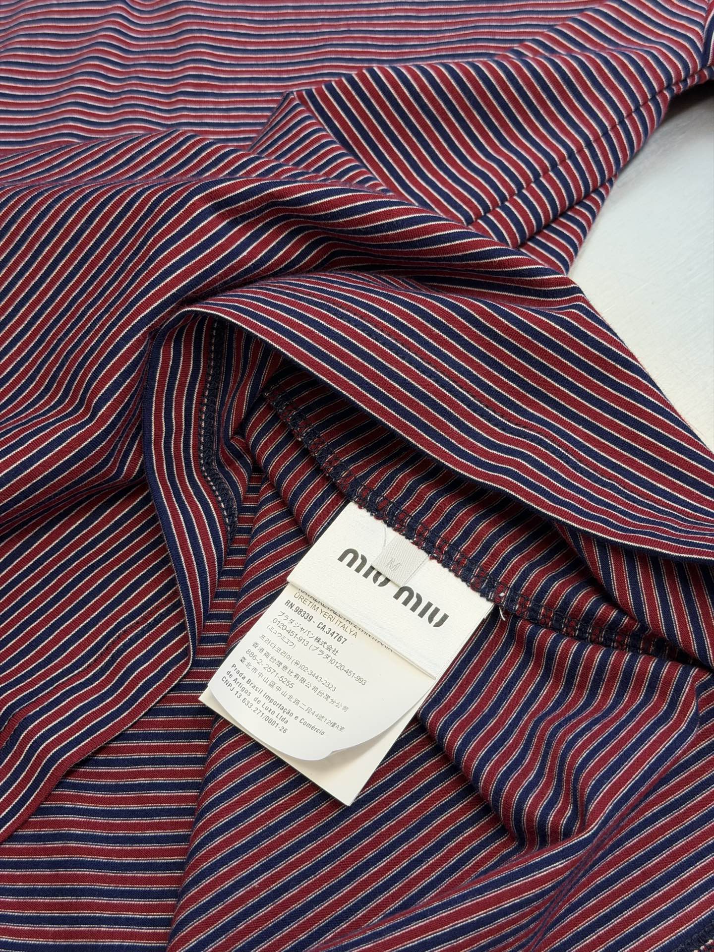 Miu logo striped henley collar long sleeves Customized textured plain weave cotton, intertwined green and burgundy thin strips of warp and weft, layered colors, classic henley half placket configuration, neat opening and closing, contrasting collar edge delicately outlines the collar, brand woven logo sewn on the left chest, loose dropped shoulders silhouette, integrating the Italian retro college heritage into the daily shape, interpreting a relaxed and elegant high-end elegance style - Image 9