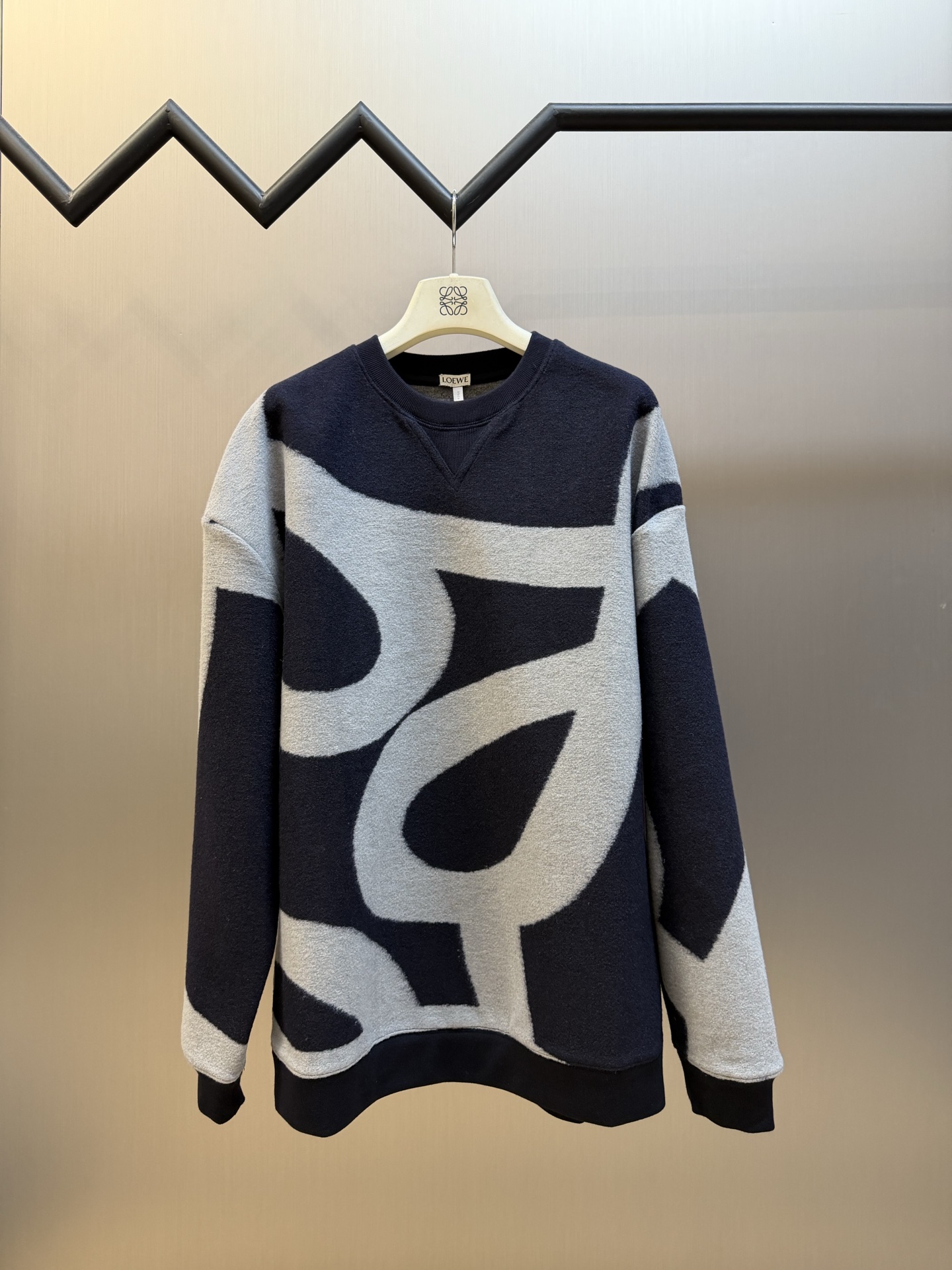 Lew Anagram embroidered jacquard sweater Custom-woven cotton blend with sequence pattern, two-color warp and weft intertwined, abstract streamlined large curve pattern spread vertically and horizontally, stretched Anagram symbol wanders freely, a small Anagram embroidery is placed in the center of the back of the neck, the stitching is even and concise, accurately annotating the brand's collection of aesthetic symbols