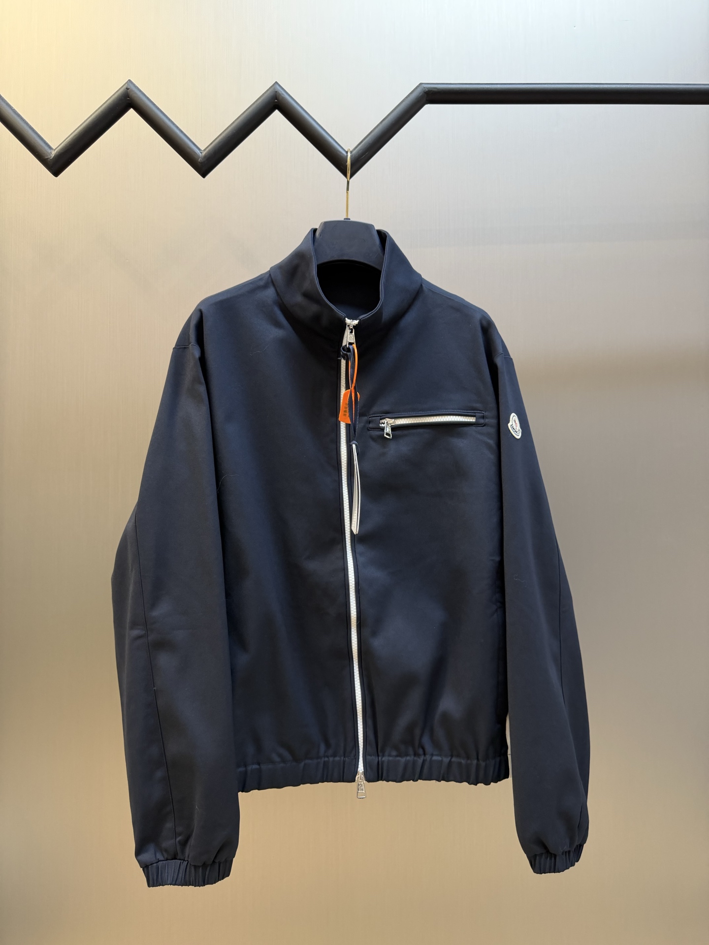 Moc logo pocket zip jacket Customized Mo Chen Yujing cotton brocade blend, three-dimensional stand-up collar creates a smart aura, the main zipper and chest pocket zipper use contrasting teeth, showing exquisite craftsmanship in details. Double green webbing runs vertically through the side of the body, injecting retro sports lines, round logos on the sleeves and arms are implicitly embellished, and elastic cuffs stabilize the version. It combines urban functionality and retro sports aesthetics, interpreting Italian quiet luxury style.