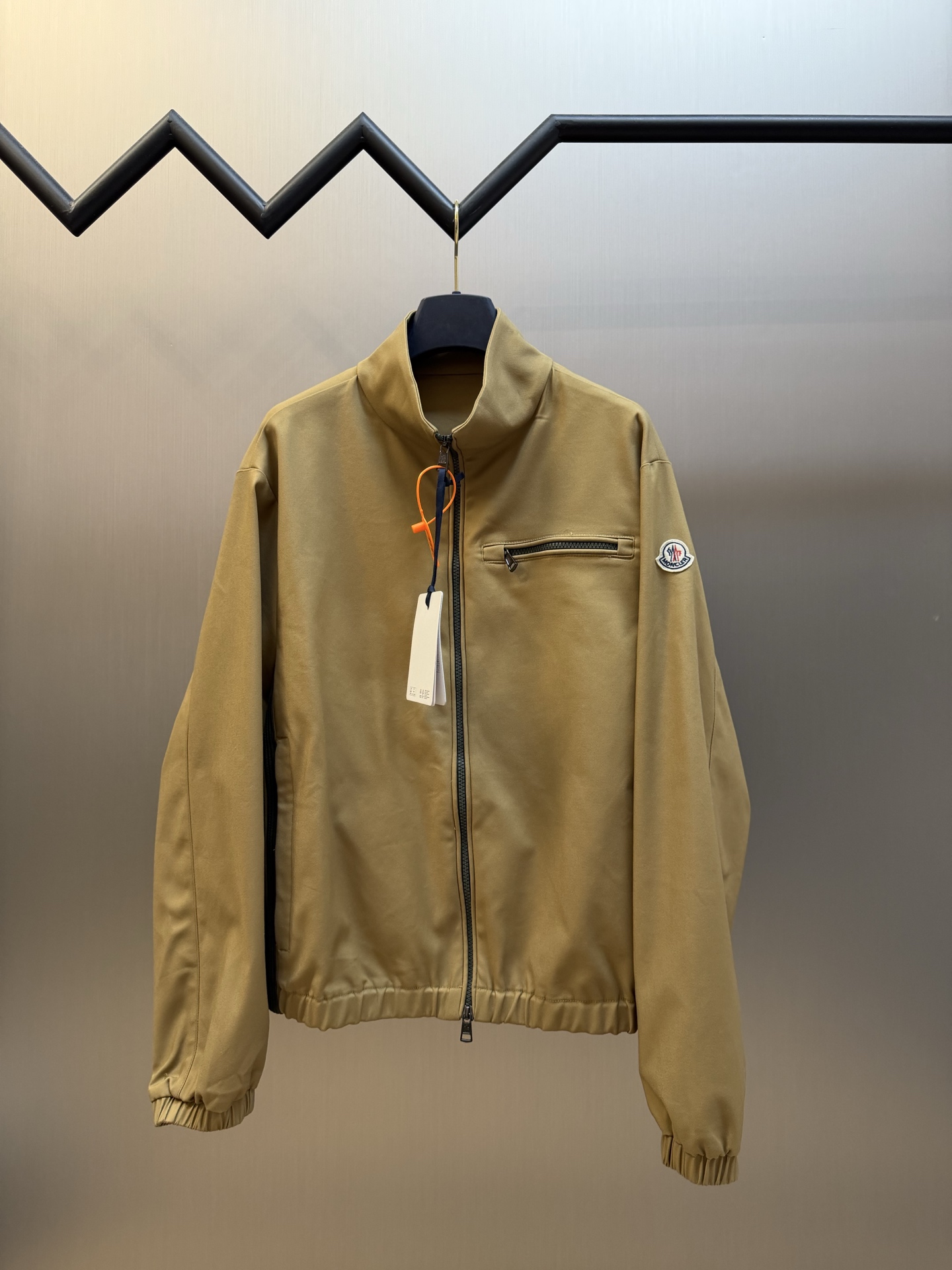 Moc logo pocket zip jacket Customized Mo Chen Yujing cotton brocade blend, three-dimensional stand-up collar creates a smart aura, the main zipper and chest pocket zipper use contrasting teeth, showing exquisite craftsmanship in details. Double green webbing runs vertically through the side of the body, injecting retro sports lines, round logos on the sleeves and arms are implicitly embellished, and elastic cuffs stabilize the version. It combines urban functionality and retro sports aesthetics, interpreting Italian quiet luxury style.