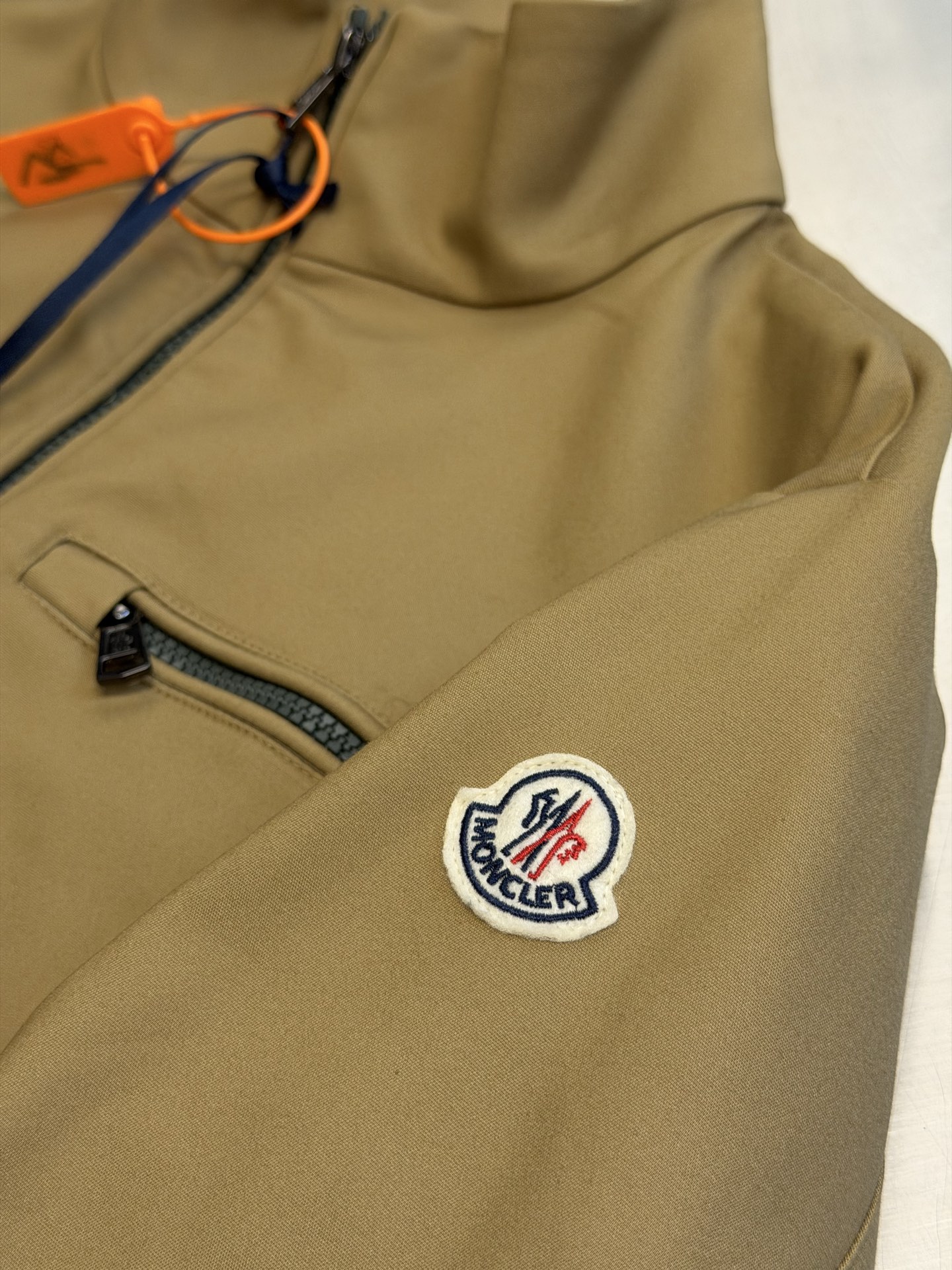 Moc logo pocket zip jacket Customized Mo Chen Yujing cotton brocade blend, three-dimensional stand-up collar creates a smart aura, the main zipper and chest pocket zipper use contrasting teeth, showing exquisite craftsmanship in details. Double green webbing runs vertically through the side of the body, injecting retro sports lines, round logos on the sleeves and arms are implicitly embellished, and elastic cuffs stabilize the version. It combines urban functionality and retro sports aesthetics, interpreting Italian quiet luxury style. - Image 8