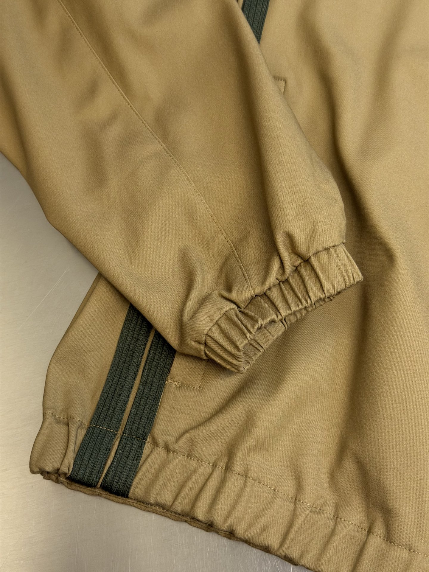 Moc logo pocket zip jacket Customized Mo Chen Yujing cotton brocade blend, three-dimensional stand-up collar creates a smart aura, the main zipper and chest pocket zipper use contrasting teeth, showing exquisite craftsmanship in details. Double green webbing runs vertically through the side of the body, injecting retro sports lines, round logos on the sleeves and arms are implicitly embellished, and elastic cuffs stabilize the version. It combines urban functionality and retro sports aesthetics, interpreting Italian quiet luxury style. - Image 9