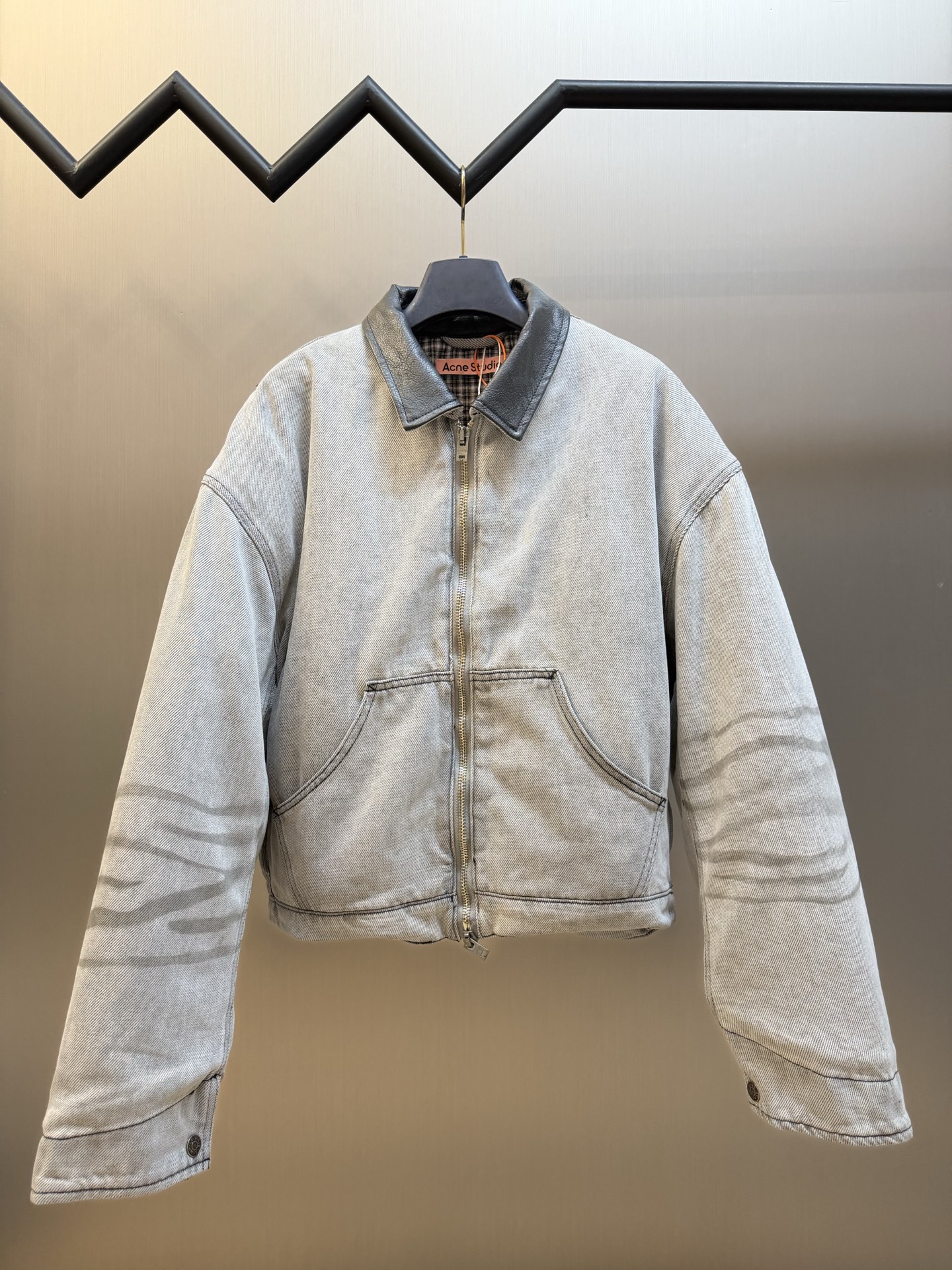 Ac Studios distressed leather cotton denim jacket The outer layer is custom-made weft-ordered organic denim, and the inner layer is custom-made domain-ordered plaid cotton. The entire body is covered in a matte gray tone. The original faded texture is naturally generated. The black leather collar is neatly cut and spliced. The roughness of the denim blends with the smoothness of the leather, creating a collision of rich layers of materials. The arms are embossed with dark patterns, and the patterns are dimly visible. The classic leather label on the back of the neck is properly seated, and the brand's collection imprint is hidden on the back.
