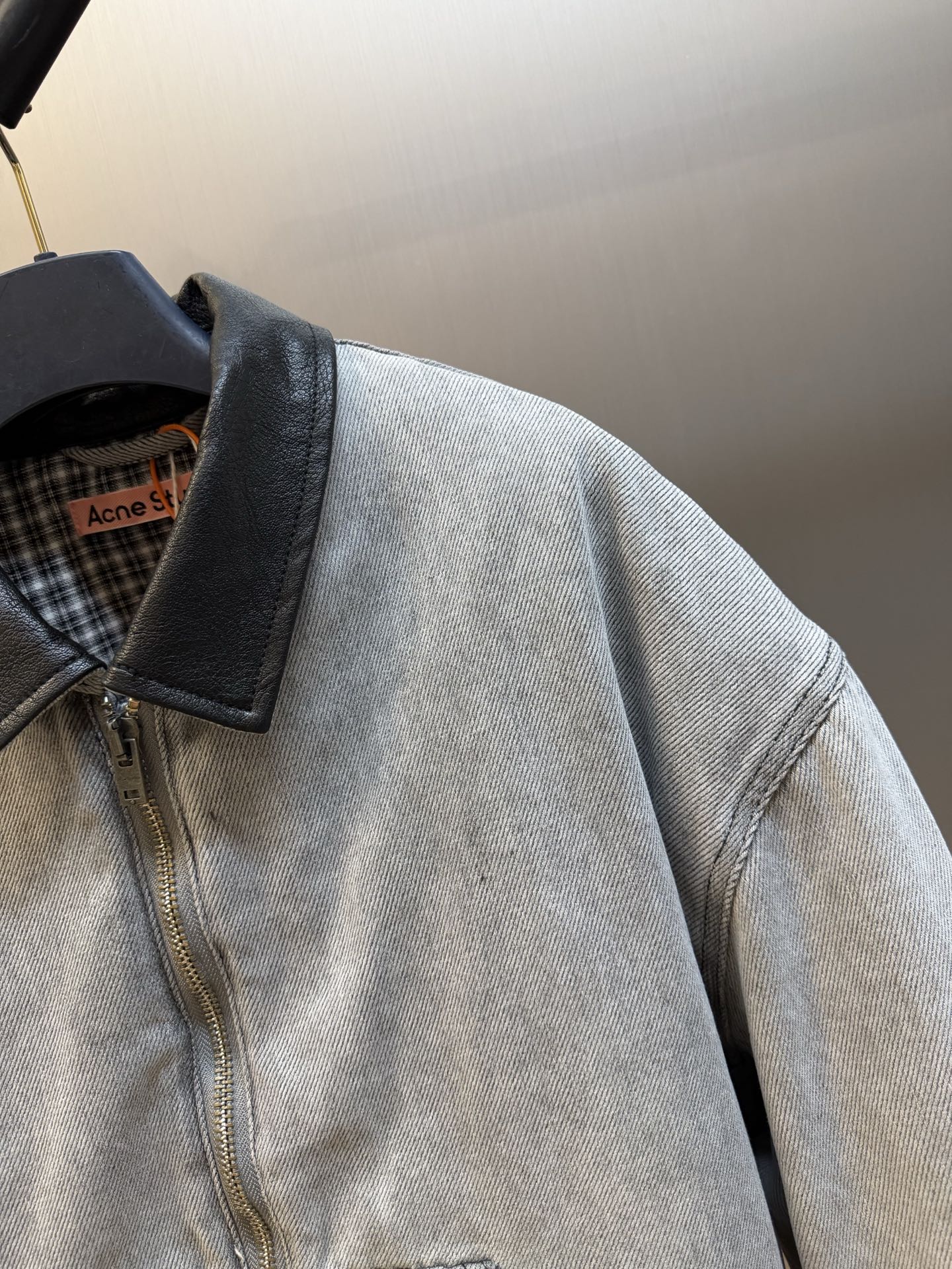 Ac Studios distressed leather cotton denim jacket The outer layer is custom-made weft-ordered organic denim, and the inner layer is custom-made domain-ordered plaid cotton. The entire body is covered in a matte gray tone. The original faded texture is naturally generated. The black leather collar is neatly cut and spliced. The roughness of the denim blends with the smoothness of the leather, creating a collision of rich layers of materials. The arms are embossed with dark patterns, and the patterns are dimly visible. The classic leather label on the back of the neck is properly seated, and the brand's collection imprint is hidden on the back. - Image 3
