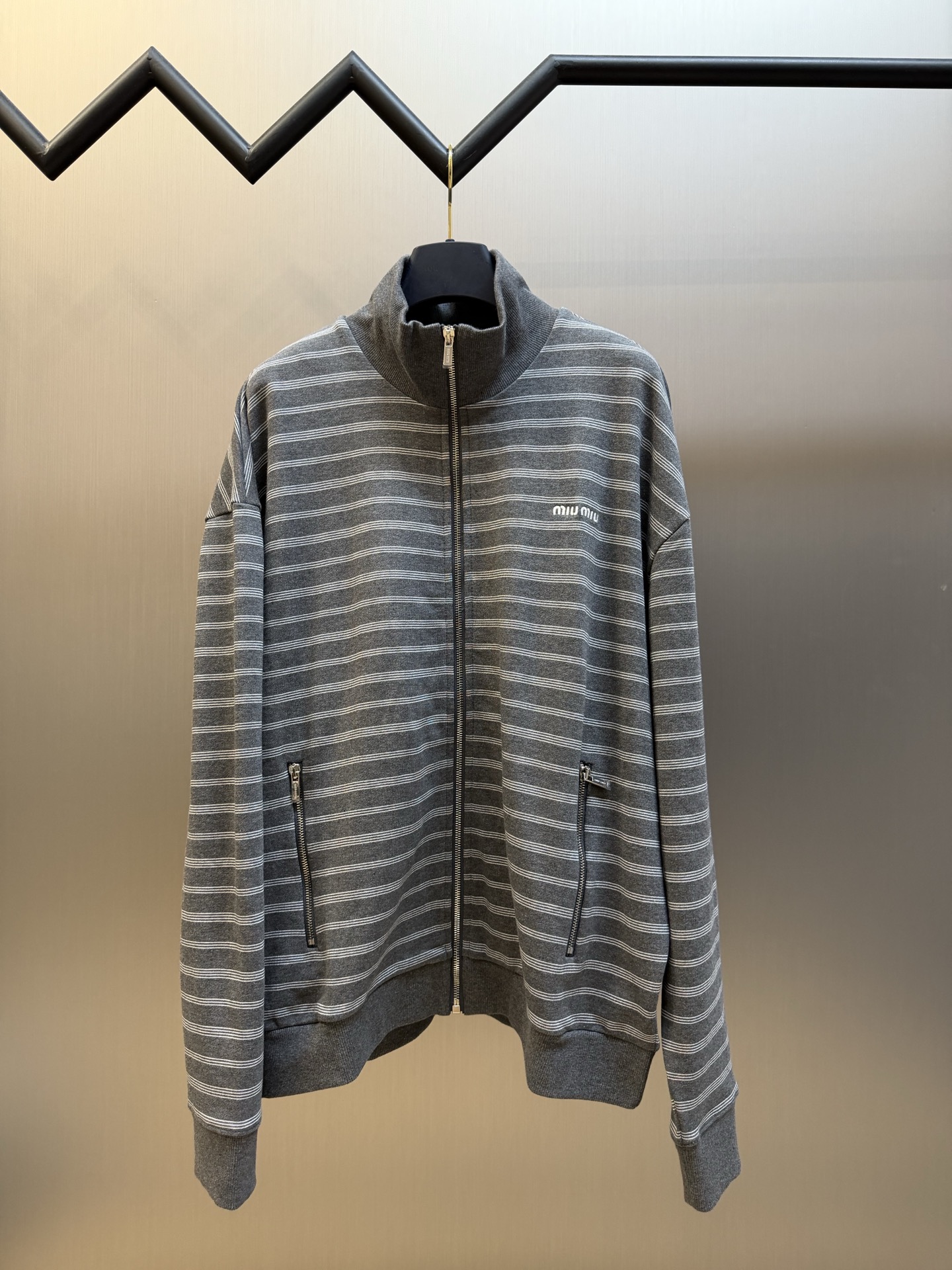 Miu gray and white striped stand collar zipper jacket White and gray interwoven jacquard terry bottom fabric, the main body is made of 24-count double yarn as the top layer, and the bottom layer is 10-count roving terry, with a weight of 380g/m²; the rib part uses a 21-count 2×2 structure, with a weight of 380g/m²