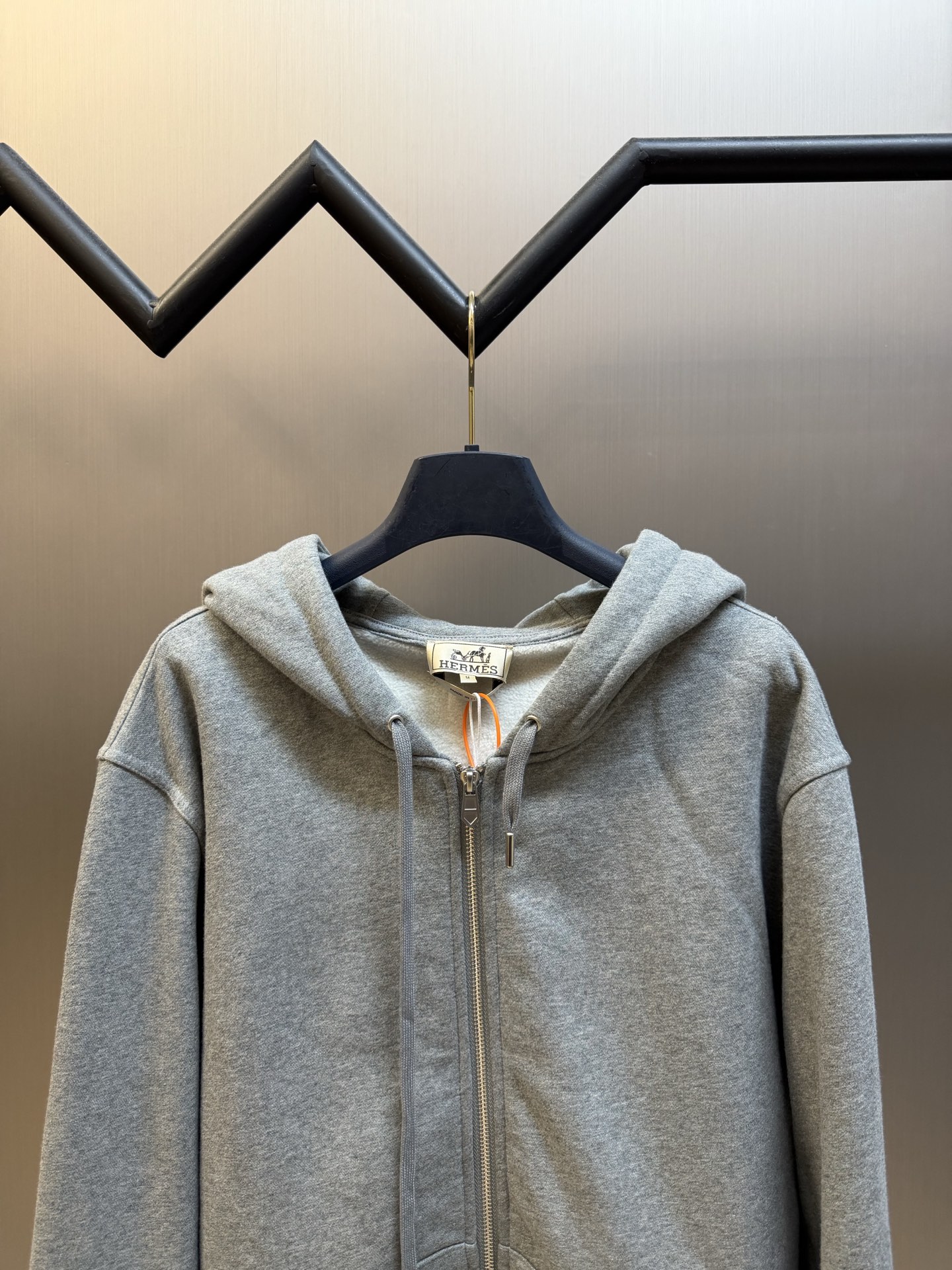Hermès appliqué zippered jacket Customized wadding and heavy cotton velvet, a neat full-open zipper creates a smooth hooded configuration, the drawstring of the same color can be adjusted to the shape of the hood, and the kangaroo pocket hides practical ingenuity. The back is embellished with deconstructed equestrian totem patch printing, and the classic carriage and spur patterns are reconstructed through perspective art, laying out the brand's century-old equestrian heritage in the calm texture. - Image 2