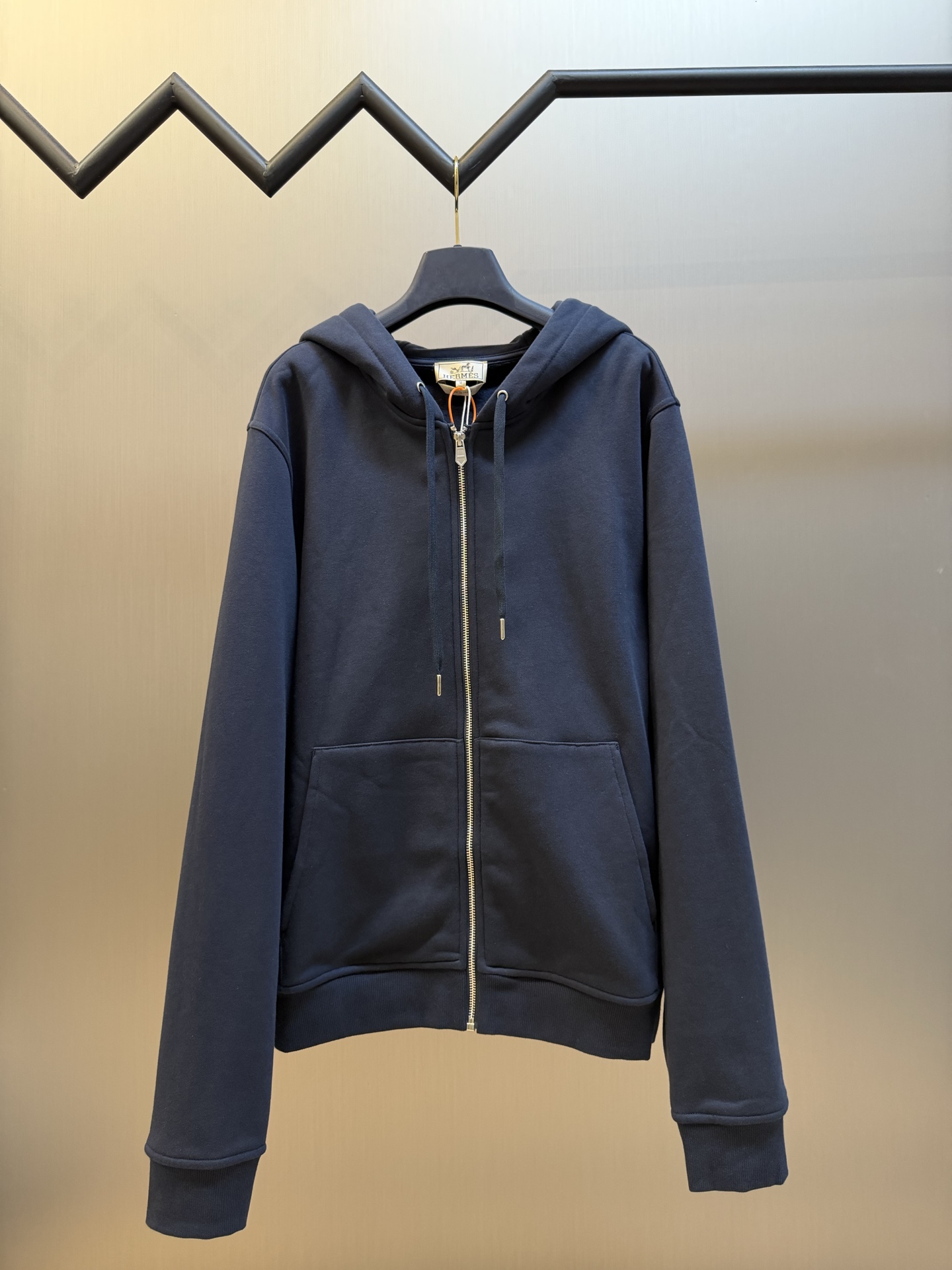 Hermès appliqué zippered jacket Customized wadding and heavy cotton velvet, a neat full-open zipper creates a smooth hooded configuration, the drawstring of the same color can be adjusted to the shape of the hood, and the kangaroo pocket hides practical ingenuity. The back is embellished with deconstructed equestrian totem patch printing, and the classic carriage and spur patterns are reconstructed through perspective art, laying out the brand's century-old equestrian heritage in the calm texture.