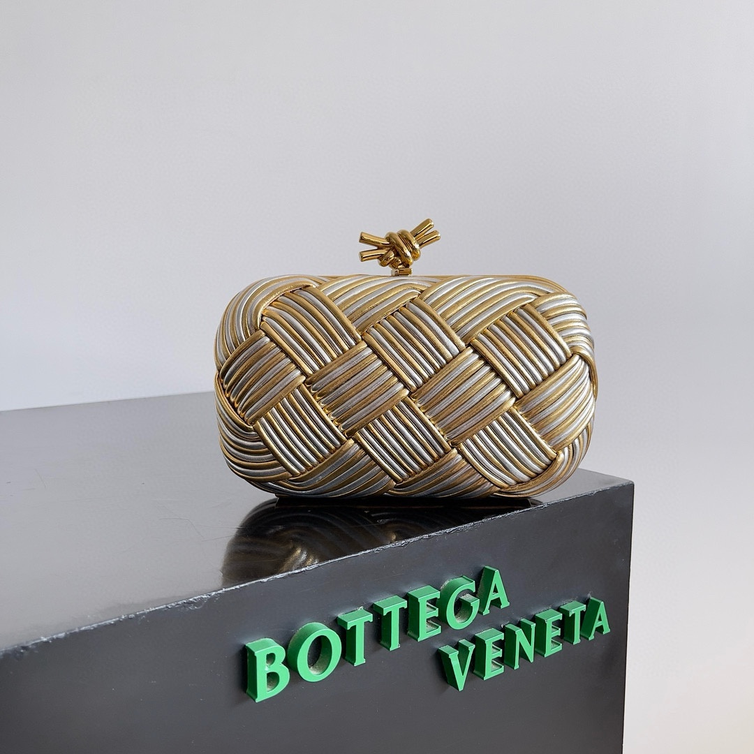 B.V. π Knot Evening Clutch This clutch is crafted from interwoven strips of gold and silver two-tone leather, paired with the iconic Knot metal twist detail and structured frame design.