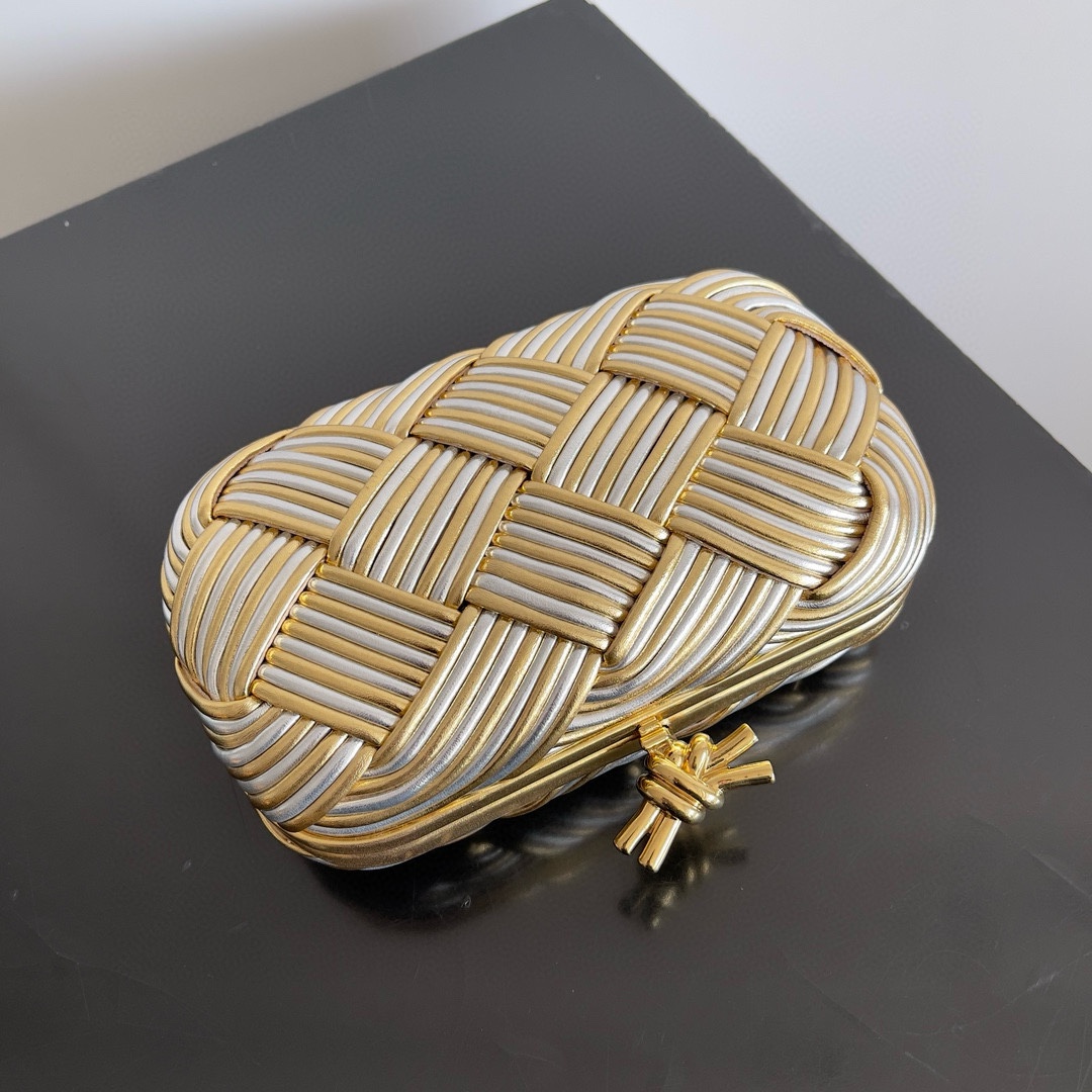 B.V. π Knot Evening Clutch This clutch is crafted from interwoven strips of gold and silver two-tone leather, paired with the iconic Knot metal twist detail and structured frame design. - Image 2