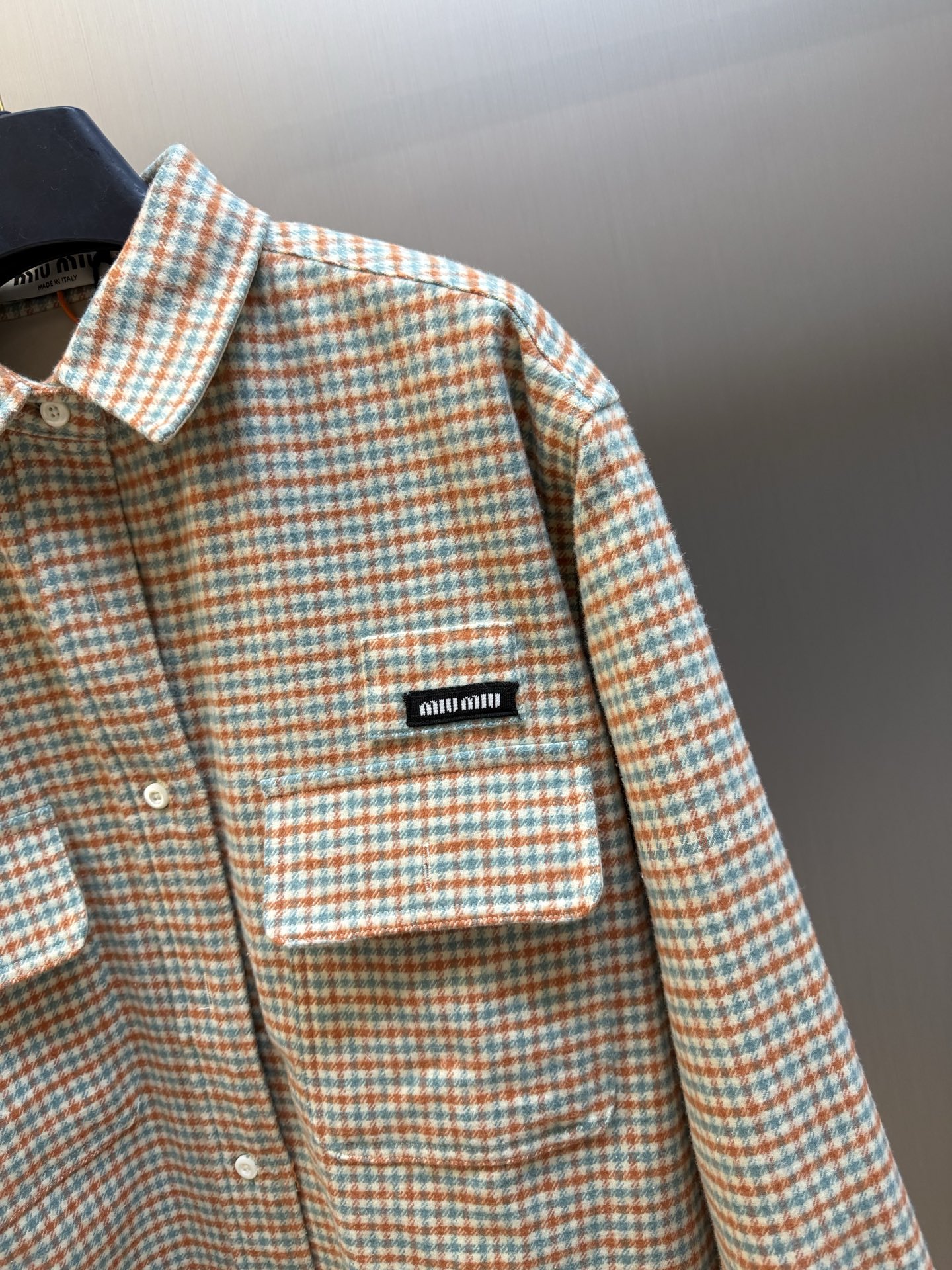 Miu logo checked shirt jacket Customized amber wool blend, woven with orange ocher and mint green warp and weft, fine yarn-dyed small plaid spreads over the body, matte fabric surface exuding Italian college retro charm, double patch pockets on the chest draping, integrating style layering and storage practicality, black embellished on the patch pockets The woven label logo is hidden in the staggered plaid texture, engraving the brand's family genes in every square inch - Image 3