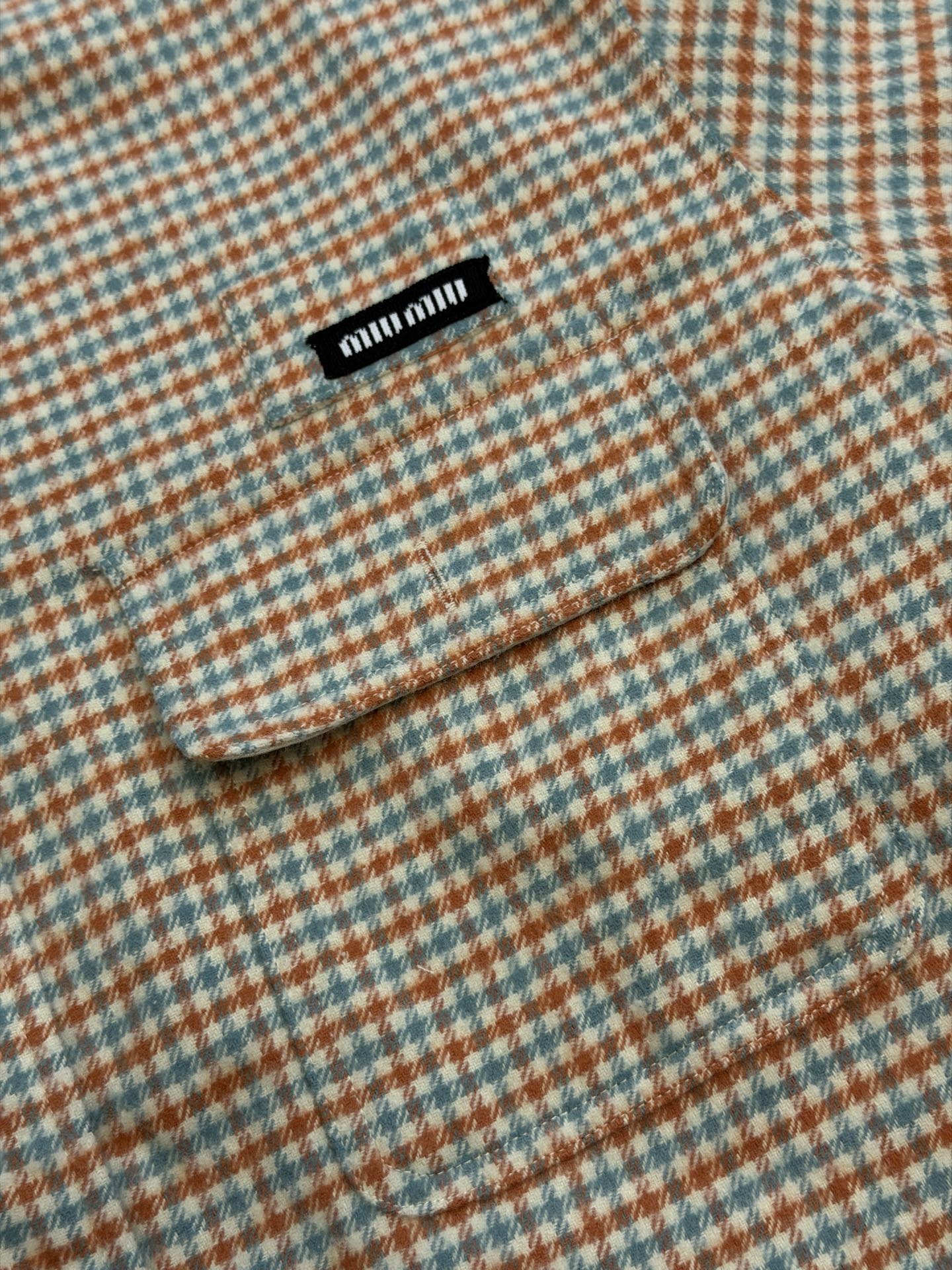 Miu logo checked shirt jacket Customized amber wool blend, woven with orange ocher and mint green warp and weft, fine yarn-dyed small plaid spreads over the body, matte fabric surface exuding Italian college retro charm, double patch pockets on the chest draping, integrating style layering and storage practicality, black embellished on the patch pockets The woven label logo is hidden in the staggered plaid texture, engraving the brand's family genes in every square inch - Image 7