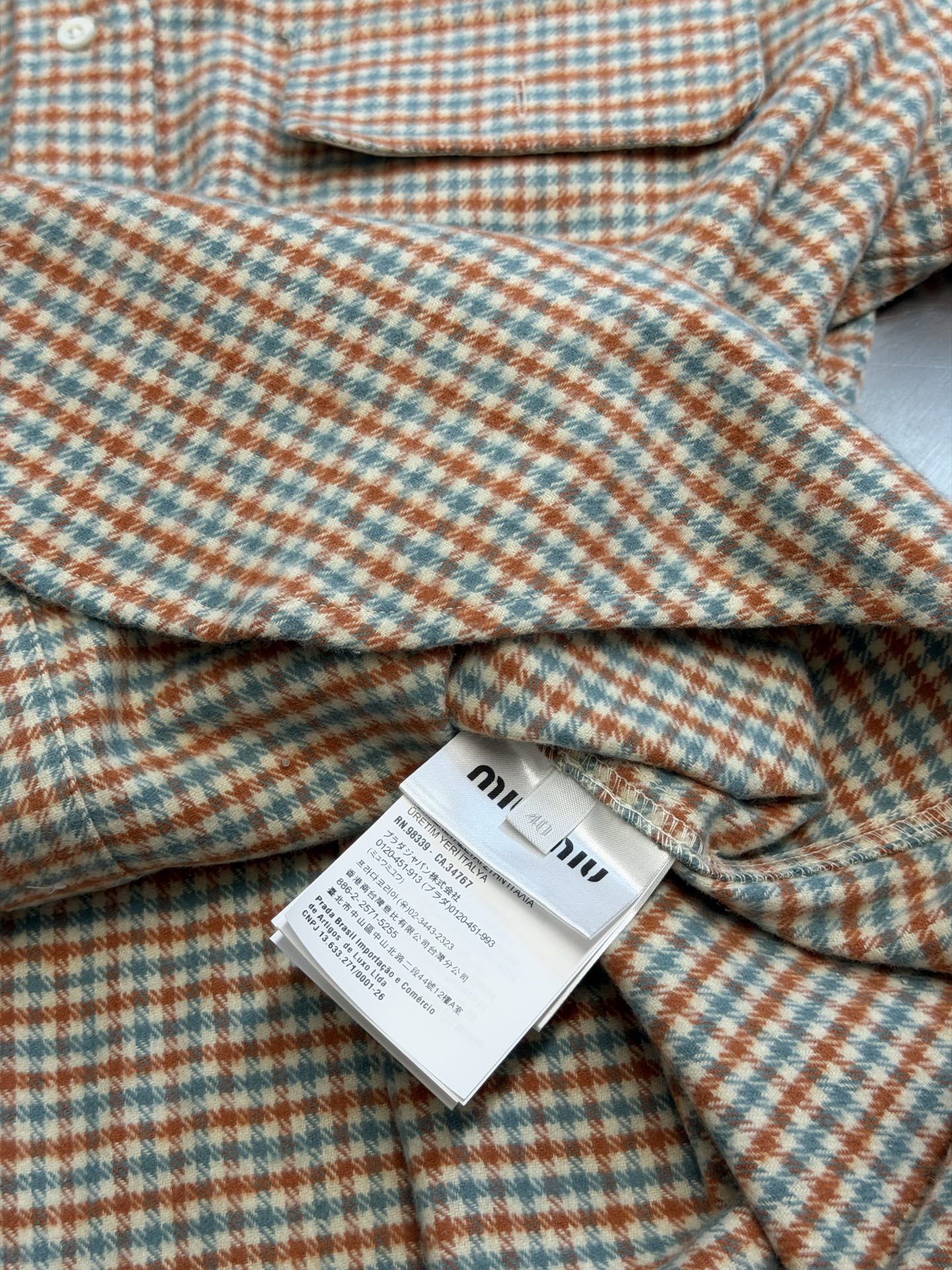 Miu logo checked shirt jacket Customized amber wool blend, woven with orange ocher and mint green warp and weft, fine yarn-dyed small plaid spreads over the body, matte fabric surface exuding Italian college retro charm, double patch pockets on the chest draping, integrating style layering and storage practicality, black embellished on the patch pockets The woven label logo is hidden in the staggered plaid texture, engraving the brand's family genes in every square inch - Image 9