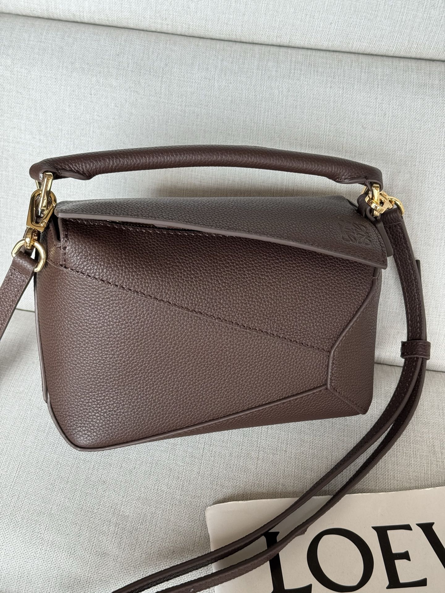 Puzzle Edge lychee brown, Handbags latest version with adjustable shoulder straps Debut handbag from Lo*we🔥* Cuboid shape and precise cutting techniques create Puzzle’s unique geometric lines* This mini version is crafted from satin calf leather with cage-stitched edges🌟 The Mini Puzzle can hold, for example, a small vertical wallet, most cell phone sizes (up to 6.1 inches), and sunglasses cases and can be worn over the shoulder or cross-body* Adjustable shoulder strap, removable* Zipper closure,* Cow leather zipper pull* Herringbone cotton canvas lining Anagram embossed 🌟 size:18*12.5*8CM Model: 3000m - Image 2