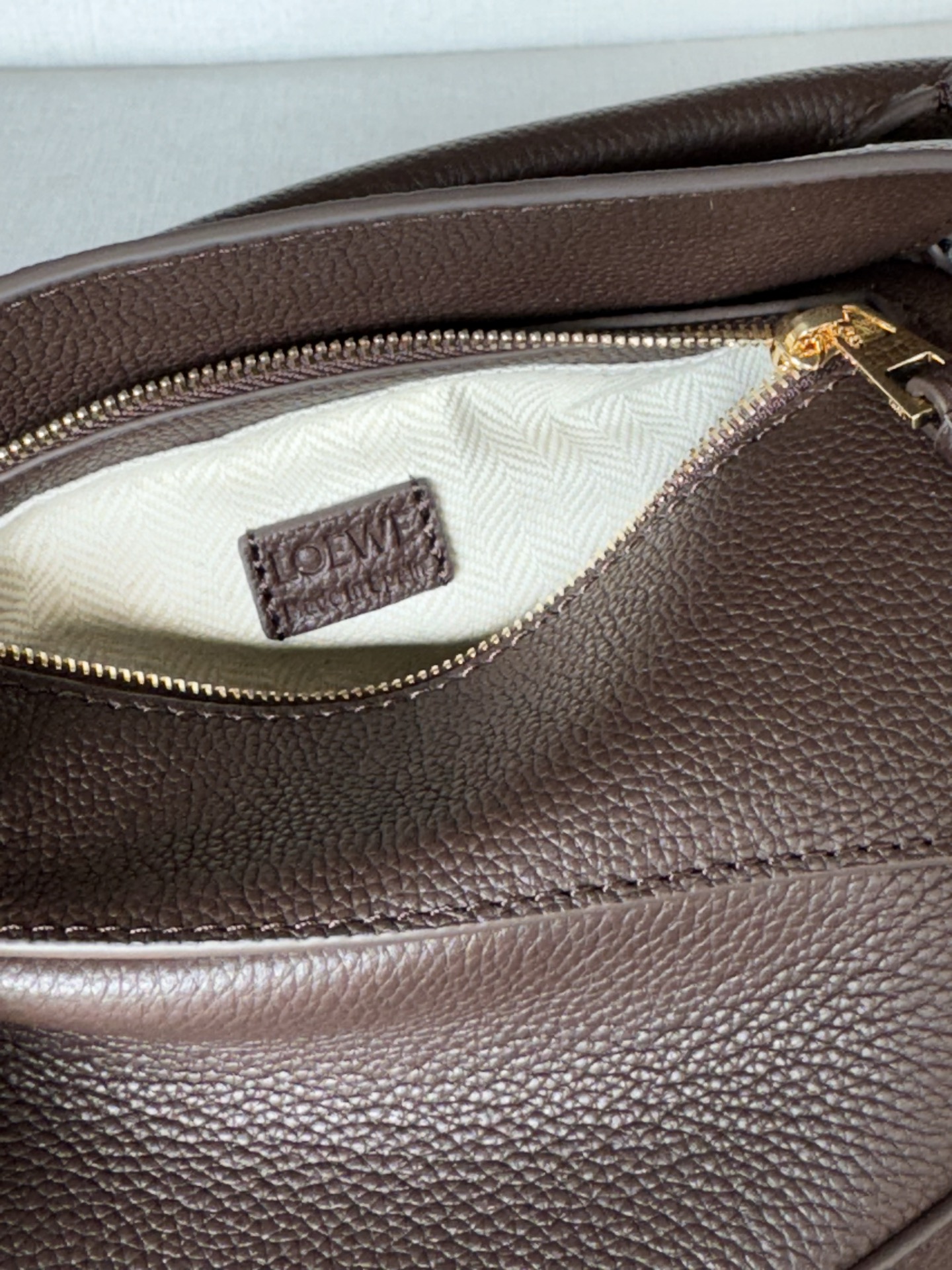 Puzzle Edge lychee brown, Handbags latest version with adjustable shoulder straps Debut handbag from Lo*we🔥* Cuboid shape and precise cutting techniques create Puzzle’s unique geometric lines* This mini version is crafted from satin calf leather with cage-stitched edges🌟 The Mini Puzzle can hold, for example, a small vertical wallet, most cell phone sizes (up to 6.1 inches), and sunglasses cases and can be worn over the shoulder or cross-body* Adjustable shoulder strap, removable* Zipper closure,* Cow leather zipper pull* Herringbone cotton canvas lining Anagram embossed 🌟 size:18*12.5*8CM Model: 3000m - Image 9