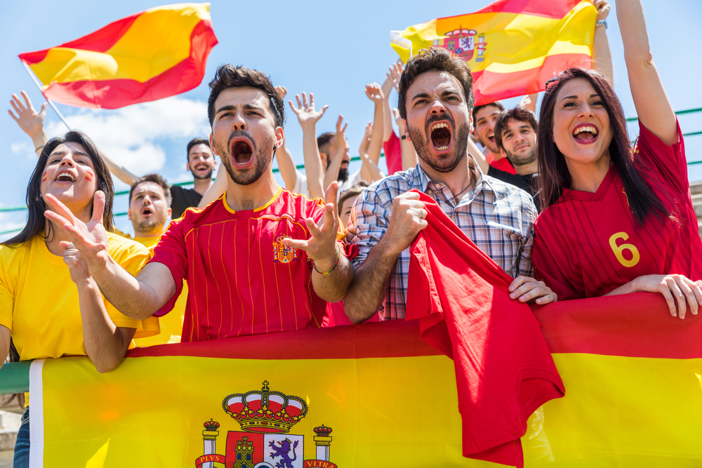 Spanish,Supporters,Cheering,At,Stadium,With,Flags.,Group,Of,Fans