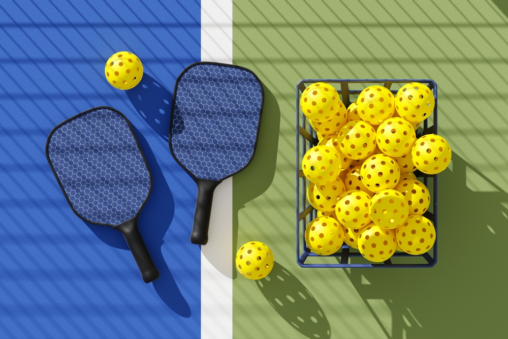 Two,Pickleball,Paddles,And,Basket,Of,Balls,On,Court,Under
