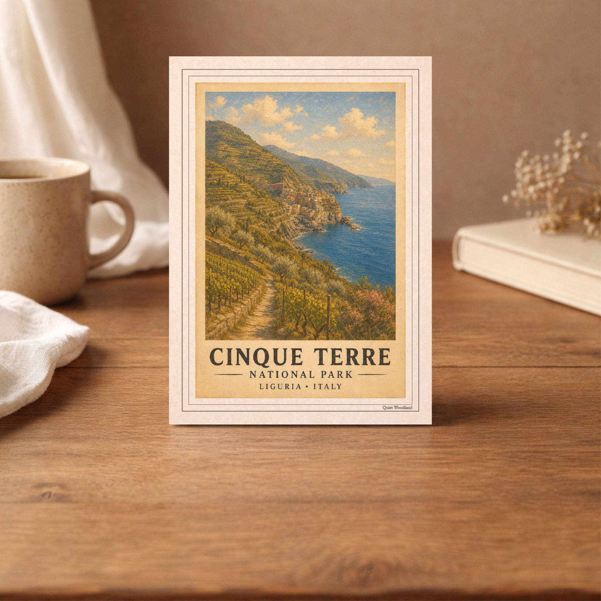 Italy National Parks Postcard Set Vintage Printable Art 2 Close-up of a 10x14 cm printable postcard showing the vintage oil painting of Cinque Terre coastal cliffs and vineyards on a wooden table.