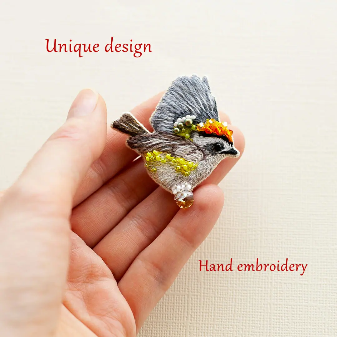 hand-embroidered bird brooch on a hand