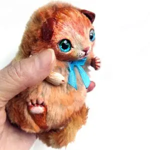 A small red kitten toy with bright turquoise eyes