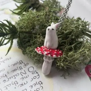 white ceramic bunny sitting on fly agaric pendant