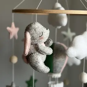 Handmade gray felt bunny from baby mobile, soft plush toy with embroidered details. Hypoallergenic nursery decor, part of Montessori-inspired crib mobile with clouds and hot air balloon