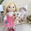 Handmade textile doll with blonde hair wearing pink corduroy dress and holding teddy bear
