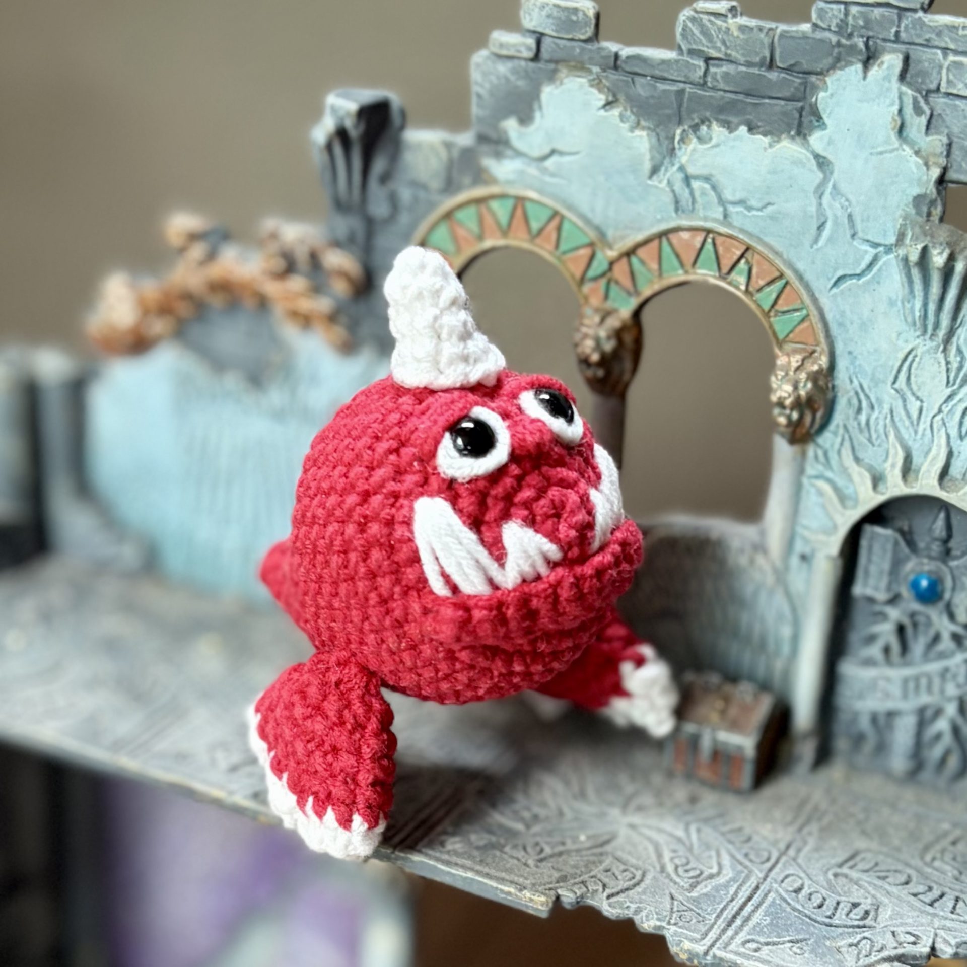 Pocket Squig Crochet Pattern. Warhammer Fantasy Amigurumi PDF 4 Crochet pattern featuring a red Warhammer Squig exploring ancient fantasy ruins beside a small treasure chest