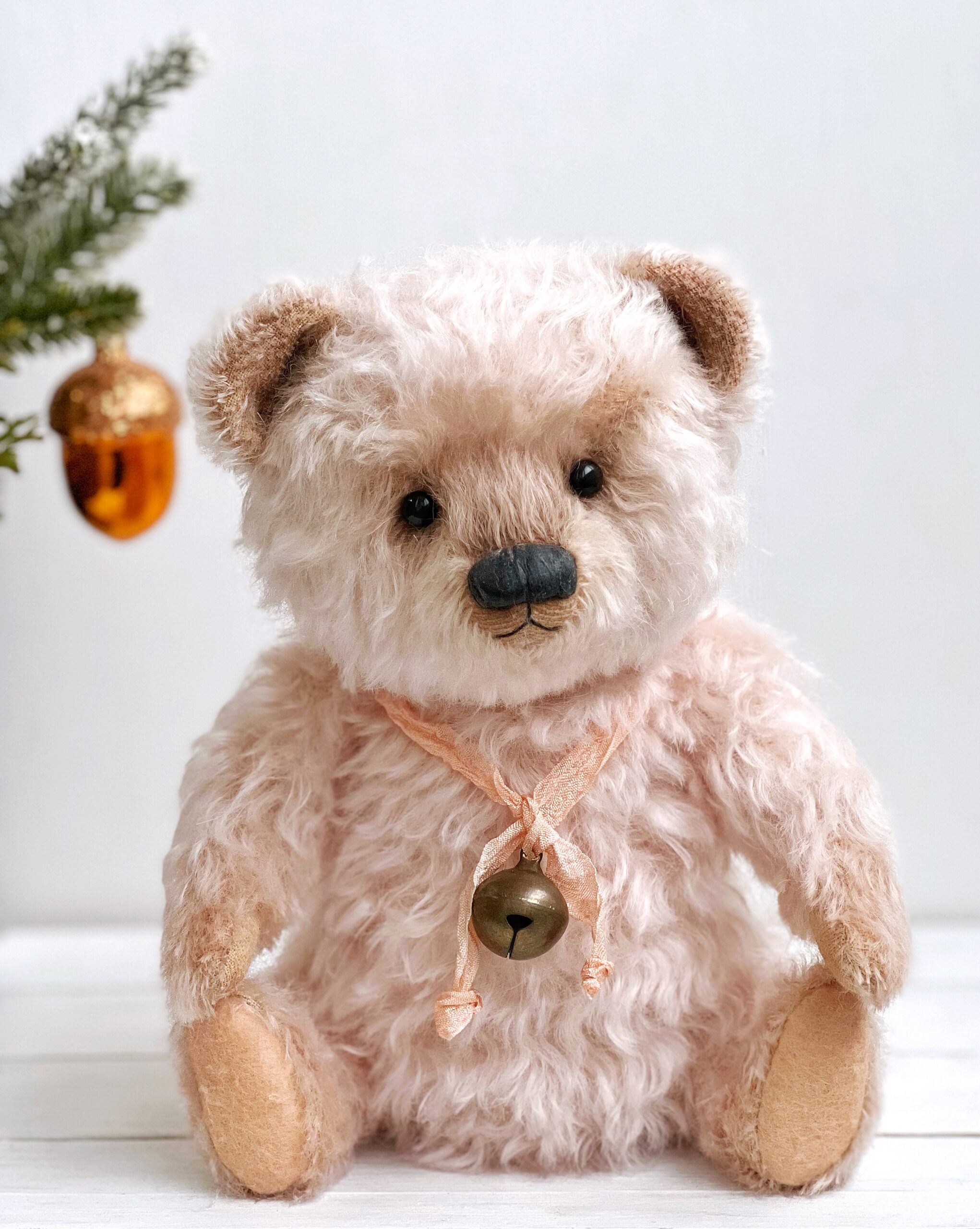 Soft pink teddy bear with a metal bell on a silk ribbon