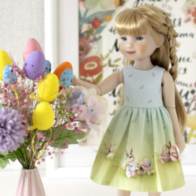 A Ruby Red Fashion Friends doll in a blue-green dress with a print of Easter bunnies and eggs for Easter