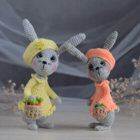 A soft toy. Two Easter bunnies are holding baskets of carrots. Rabbits in a dress and a beret.