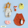 Handmade Mini Baby Bear stuffed animal in overalls and hat with baby set lying next to him: baby bottle, fox rattle, sleeping bag, bib and diaper