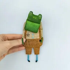 one-of-a-kind-textile-art-doll-frog-boy-in-light-brown-pants-in-hands