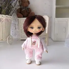 small-handmade-rag-doll-with-dark-hair-wearing-a-light-blouse-and-pink-jumpsuit
