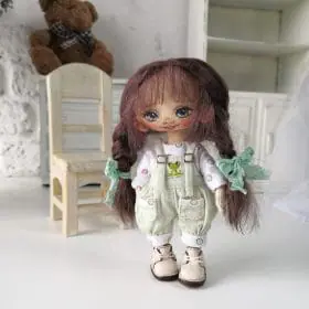 small-handmade-rag-doll-with-dark-hair-wearing-a-light-blouse-and-light-green-jumpsuit