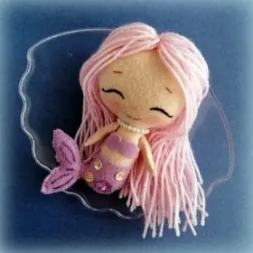 Felt toy Kelsey the chibi mermaid with long yarn hair and a tail, decorated with sequins