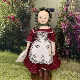 Reproduction of Izanna Walker dolls Anna in a burgundy dress.