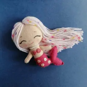 Felt toy, chibi mermaid Lorelei with long yarn hair and a tail, decorated with sequins