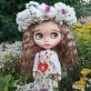 Blythe doll with brown hair, in a white dress, green apron with daisies