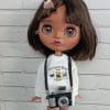 Blythe doll with short brown hair, in a white hoodie, and striped stockings, with a camera in her hands.
