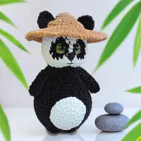 Plush crochet panda toy wearing a straw hat, handmade amigurumi pattern.