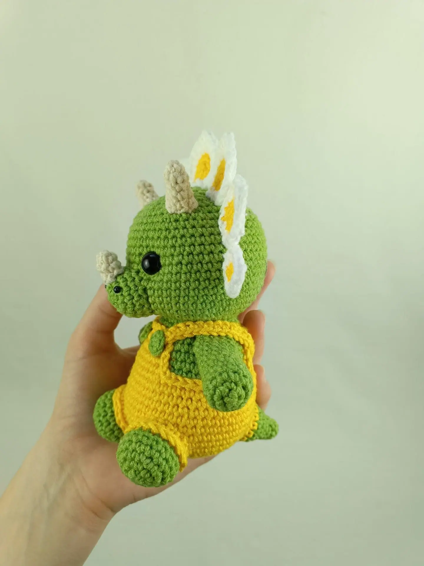 Flowers Dino Crochet Pattern Cute Triceratops Amigurumi Toy 3 Crochet plush amigurumi triceratops dinosaur with daisy flower petals and yellow overalls, digital crochet pattern.