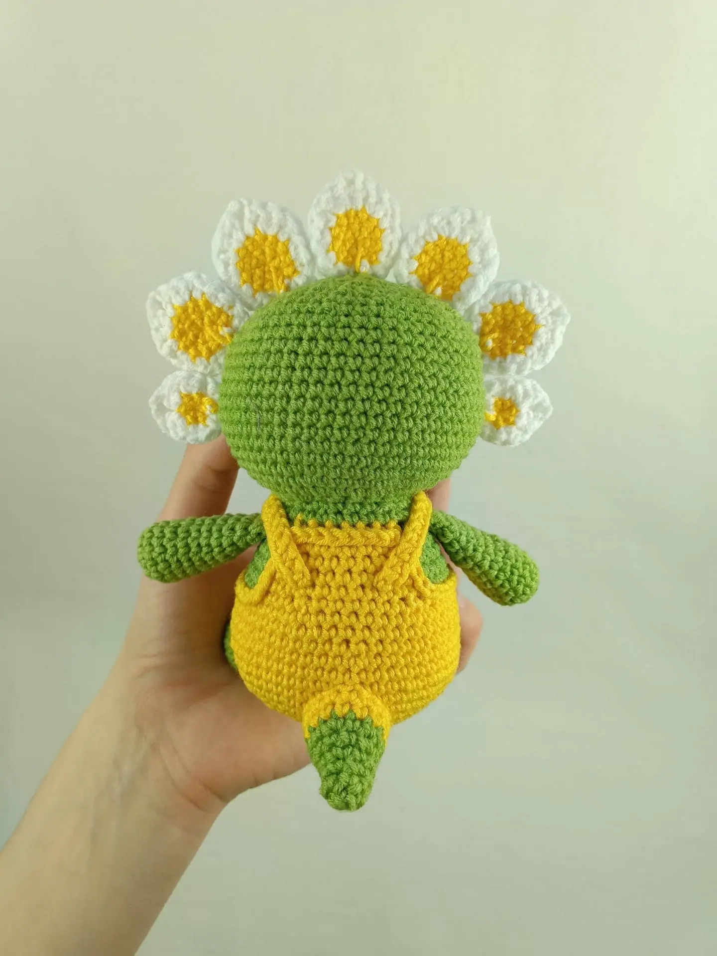 Flowers Dino Crochet Pattern Cute Triceratops Amigurumi Toy 1 Crochet plush amigurumi triceratops dinosaur with daisy flower petals and yellow overalls, digital crochet pattern.
