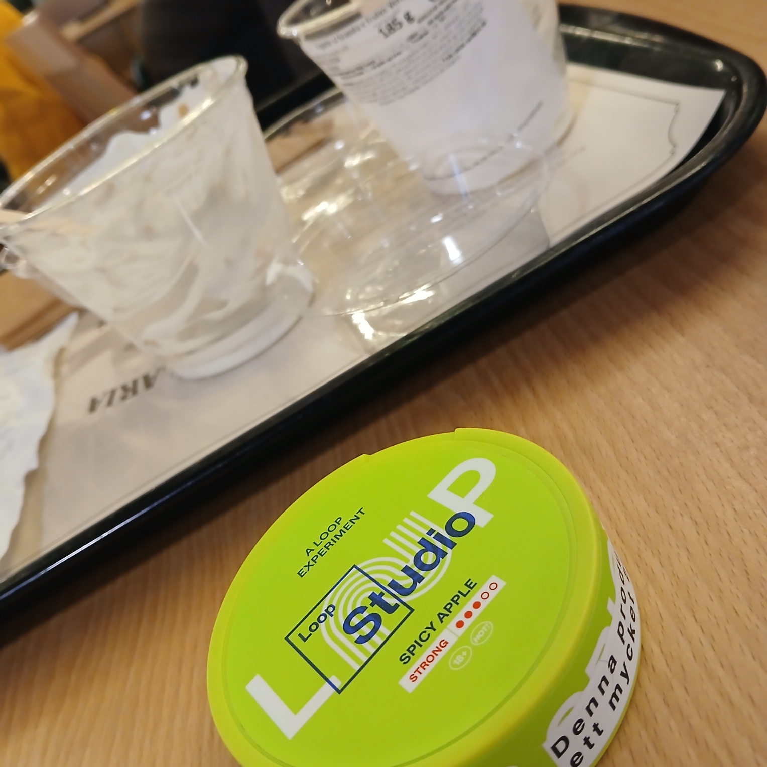 Two empty bowls of yoghurt, berries and granola consumed at the airport. And some nicotkne pouches in a lime-green can with "Spicy Apple"-flavor. We're at the Lisboa airport