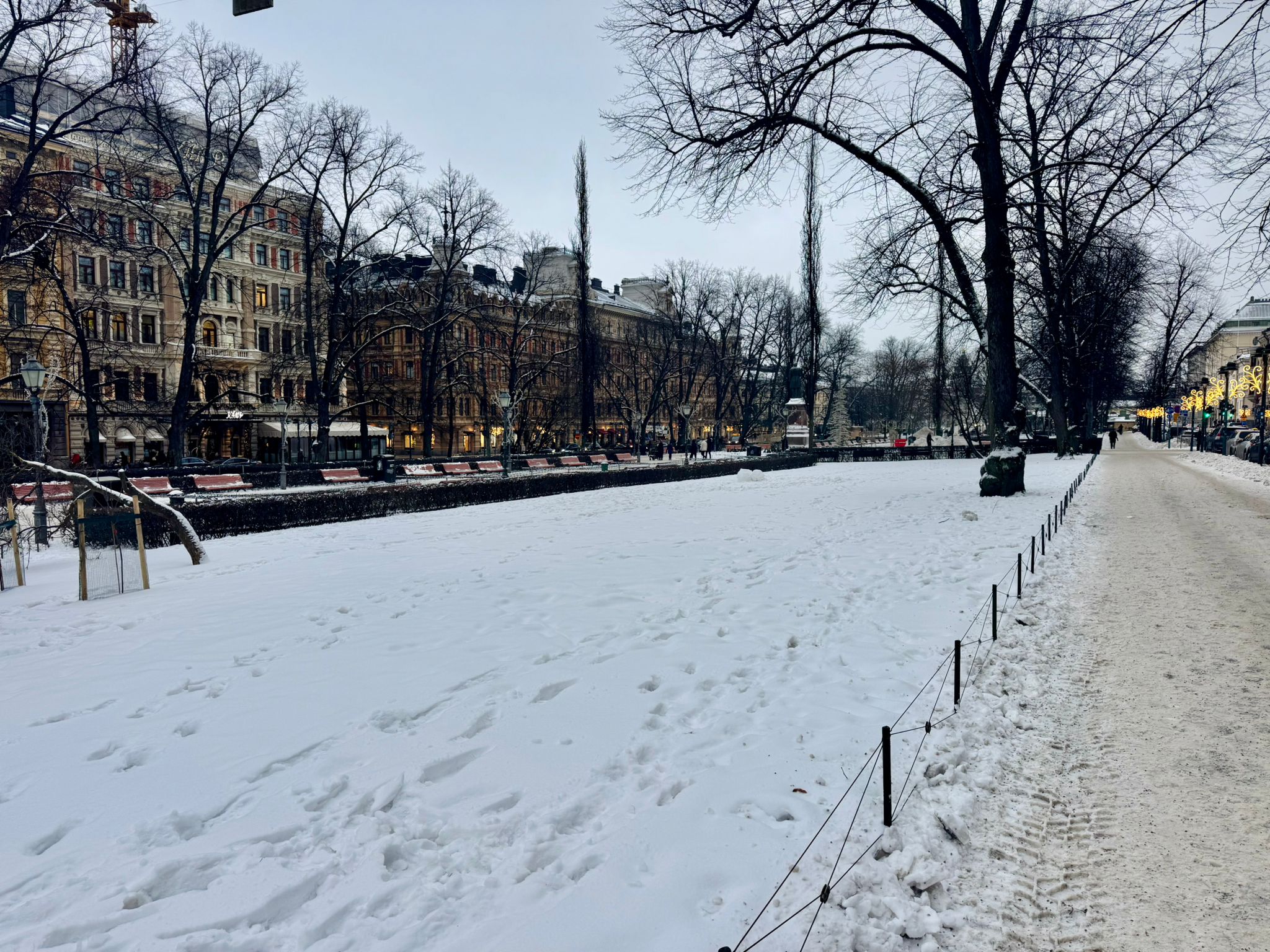 View of the snow outside in Helsinki. There are footsteps in the snow. Esplanade Park.
