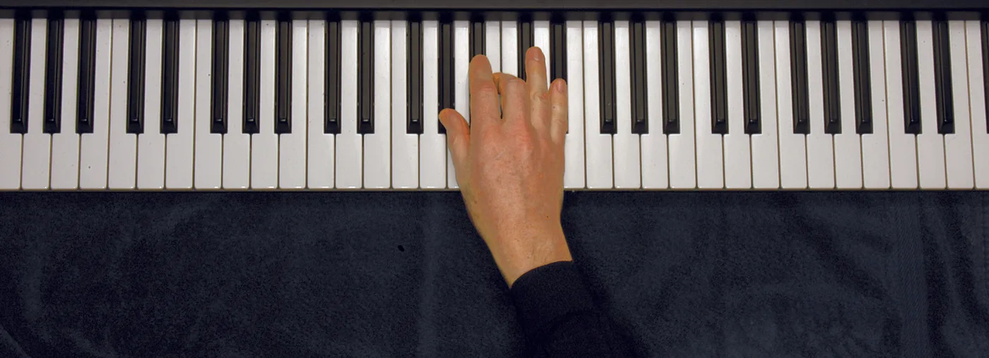 A♭m chord played on a piano — hand position on the keys