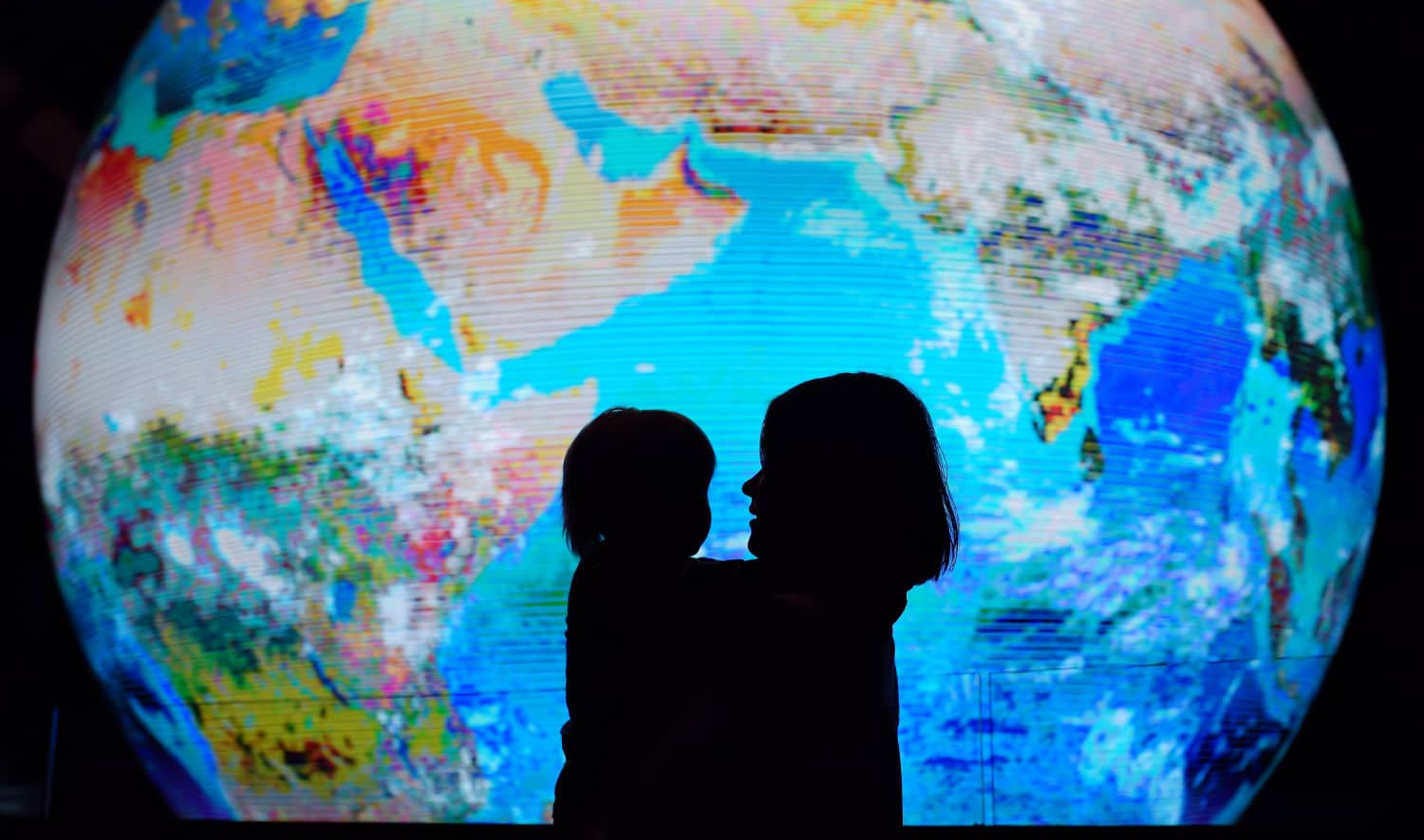 Silhouette of adult and child on background of globe earth. Ecologic and protection environment concept.