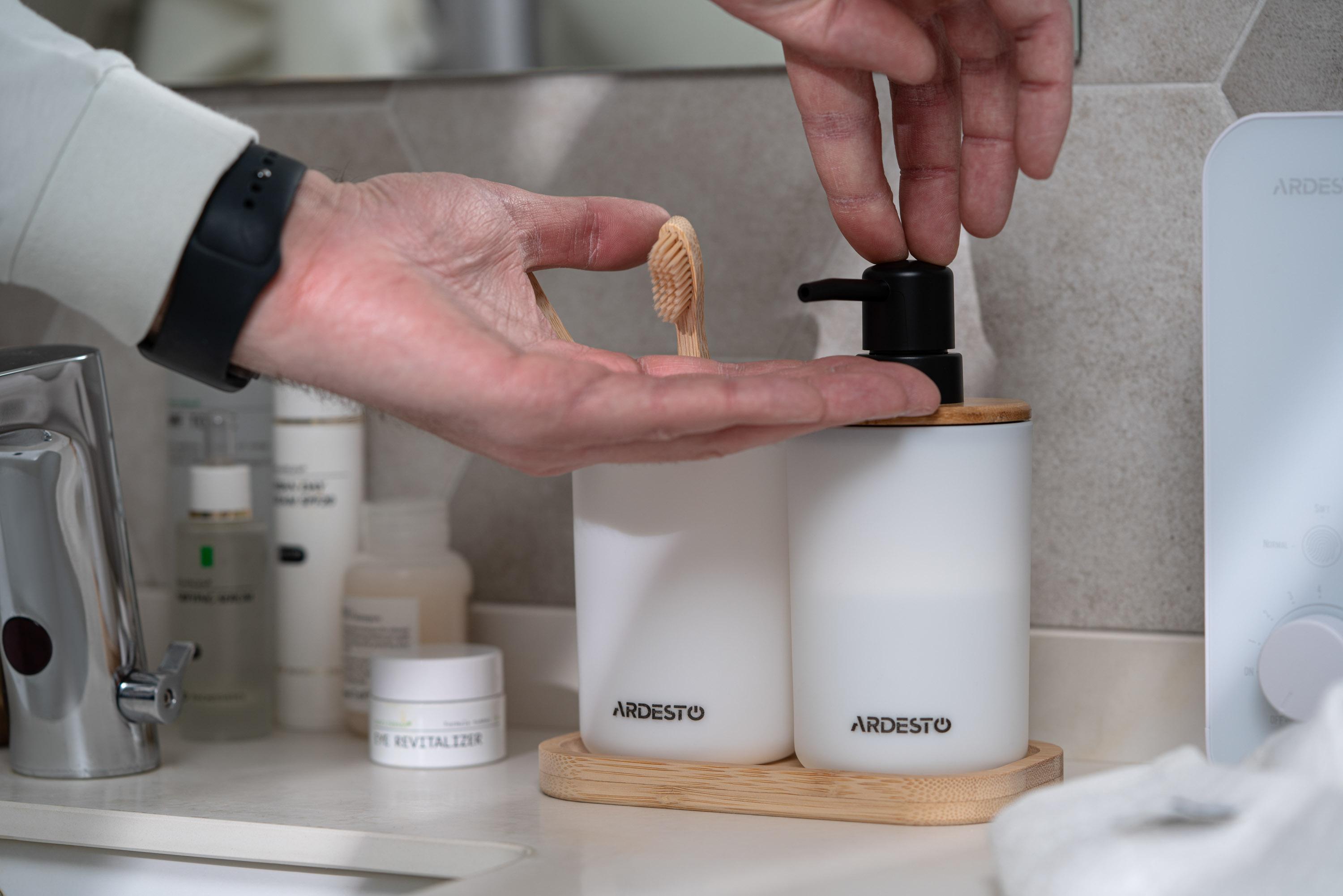 Набор для ванной комнаты с белым дозатором и стаканом на бамбуковой подставке в интерьере